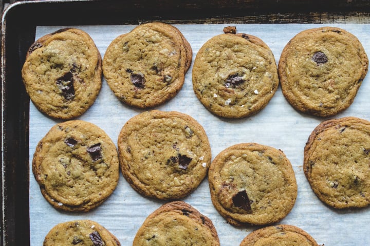 Baked chocolate chip cookies on a baking sheet with parchment paper