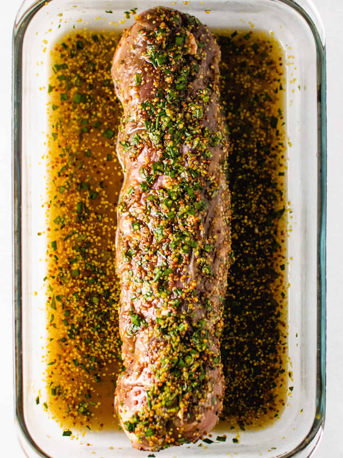 pork tenderloin marinating in a glass rectangular dish.