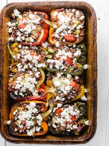 Baked stuffed peppers in clay dish with feta cheese sprinkled on top
