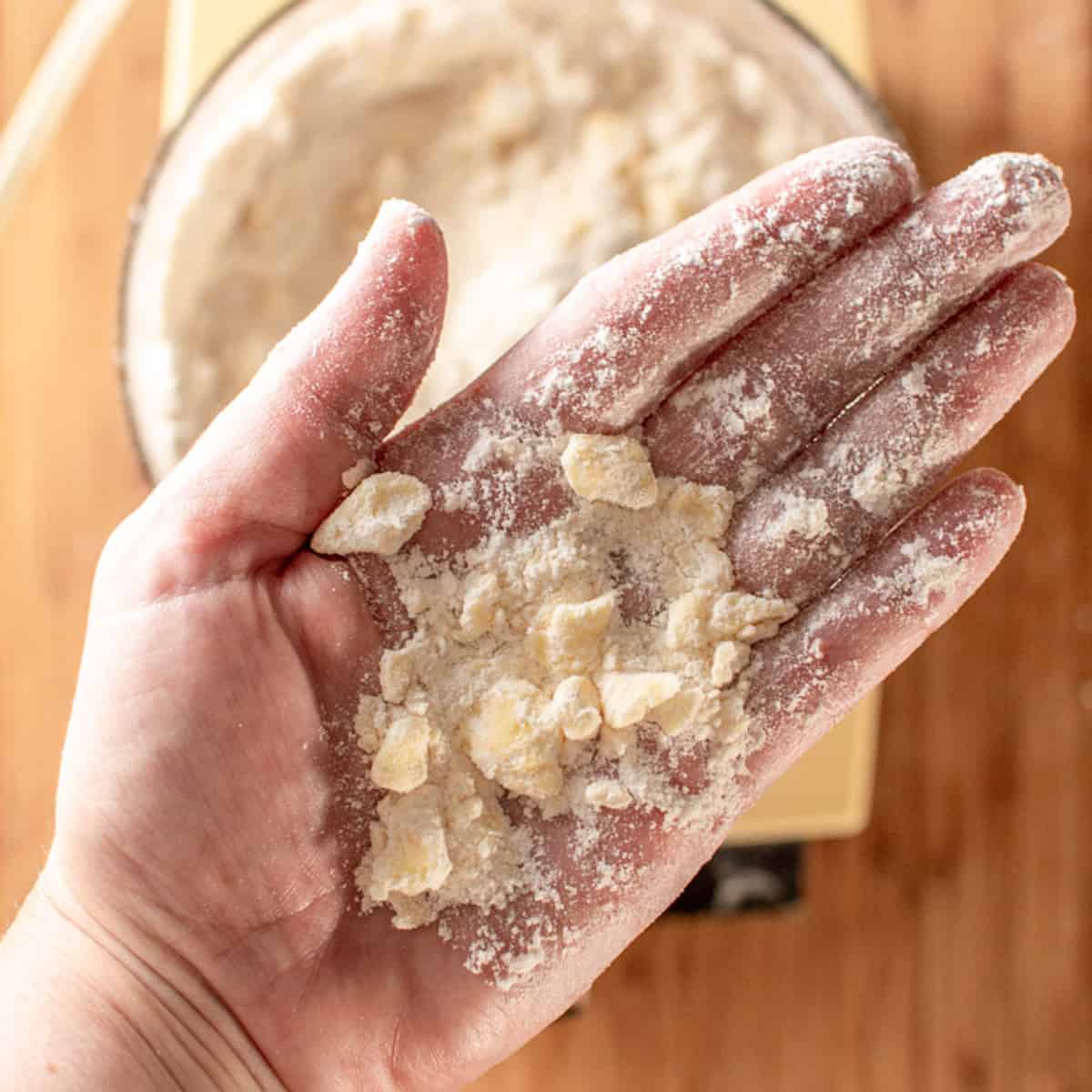 pea sized pieces of butter mixed with flour shown in the palm of a hand. 