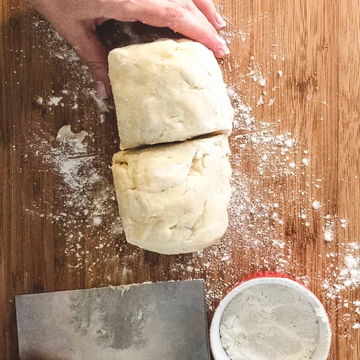 finished dough on a board shaped into a log and cut in half.