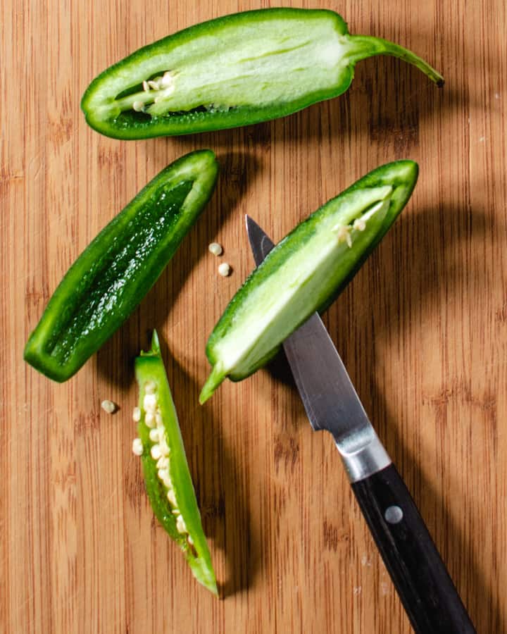 jalapeno peppers being cut on wood board