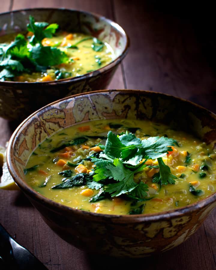two bowls of red lentil and vegetable soup garnished with cilantro