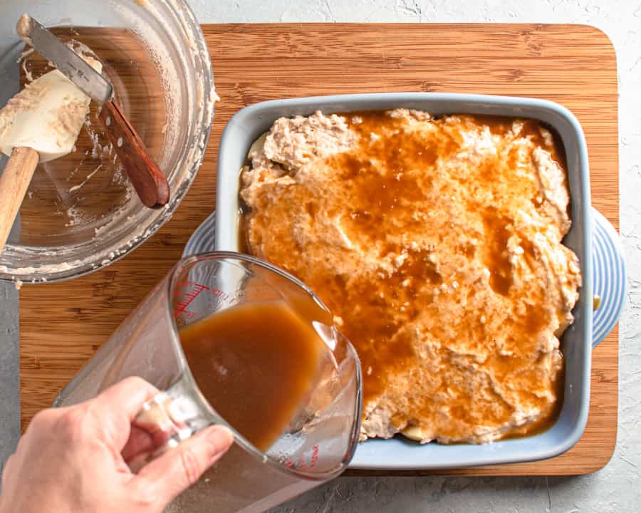 apple cake in baking dish with action shot of sauce being poured over top