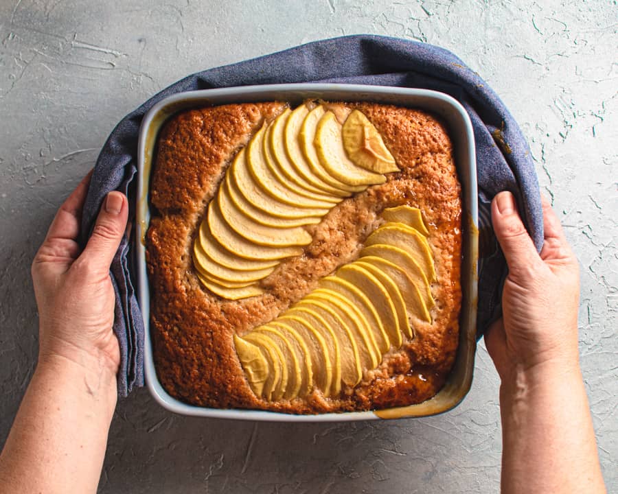 baked apple caramel pudding cake being held with a blue towel