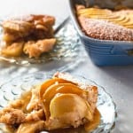 two pieces of apple caramel pudding cake on plates with cake dish in background