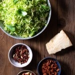 ingredients for brussels sprouts slaw in separate bowls on wood background