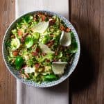 Brussels sprouts bacon and apple slaw in a round bowl on top of a cloth napkin