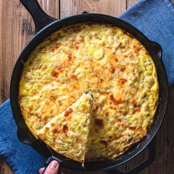 whole cauliflower and leek frittata with slice being removed