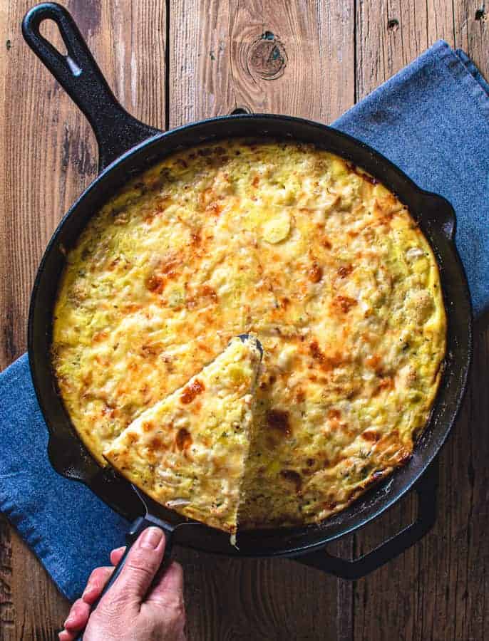 whole cauliflower and leek frittata with slice being removed