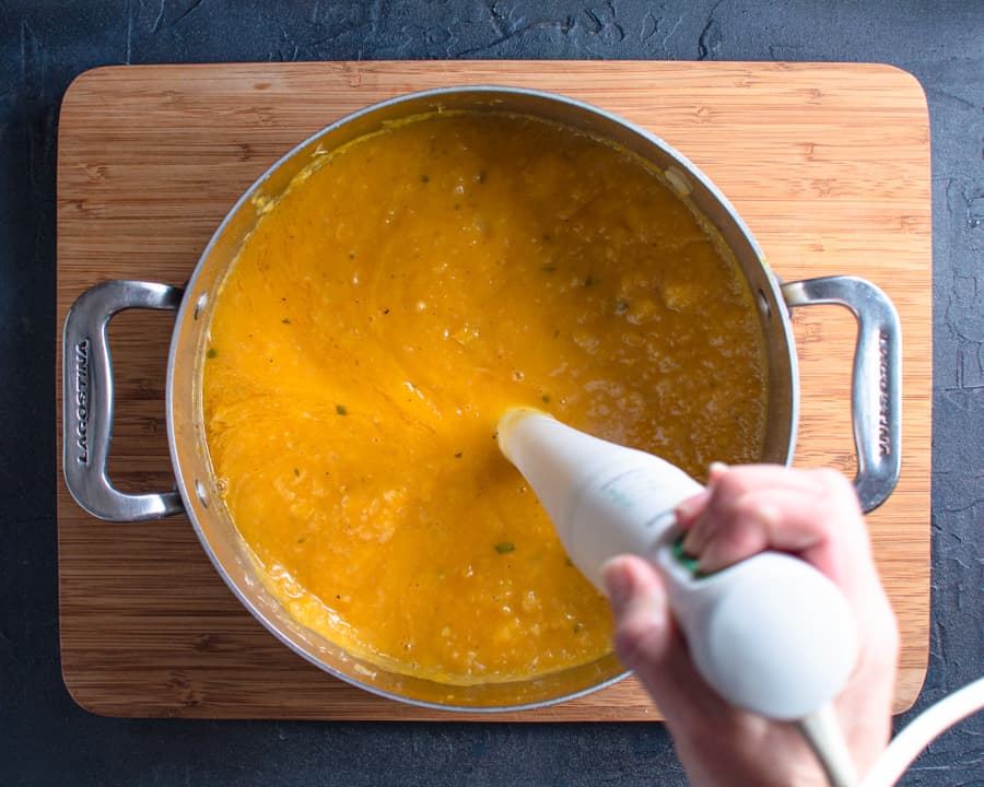 pureeing squash soup with hand blender in pot