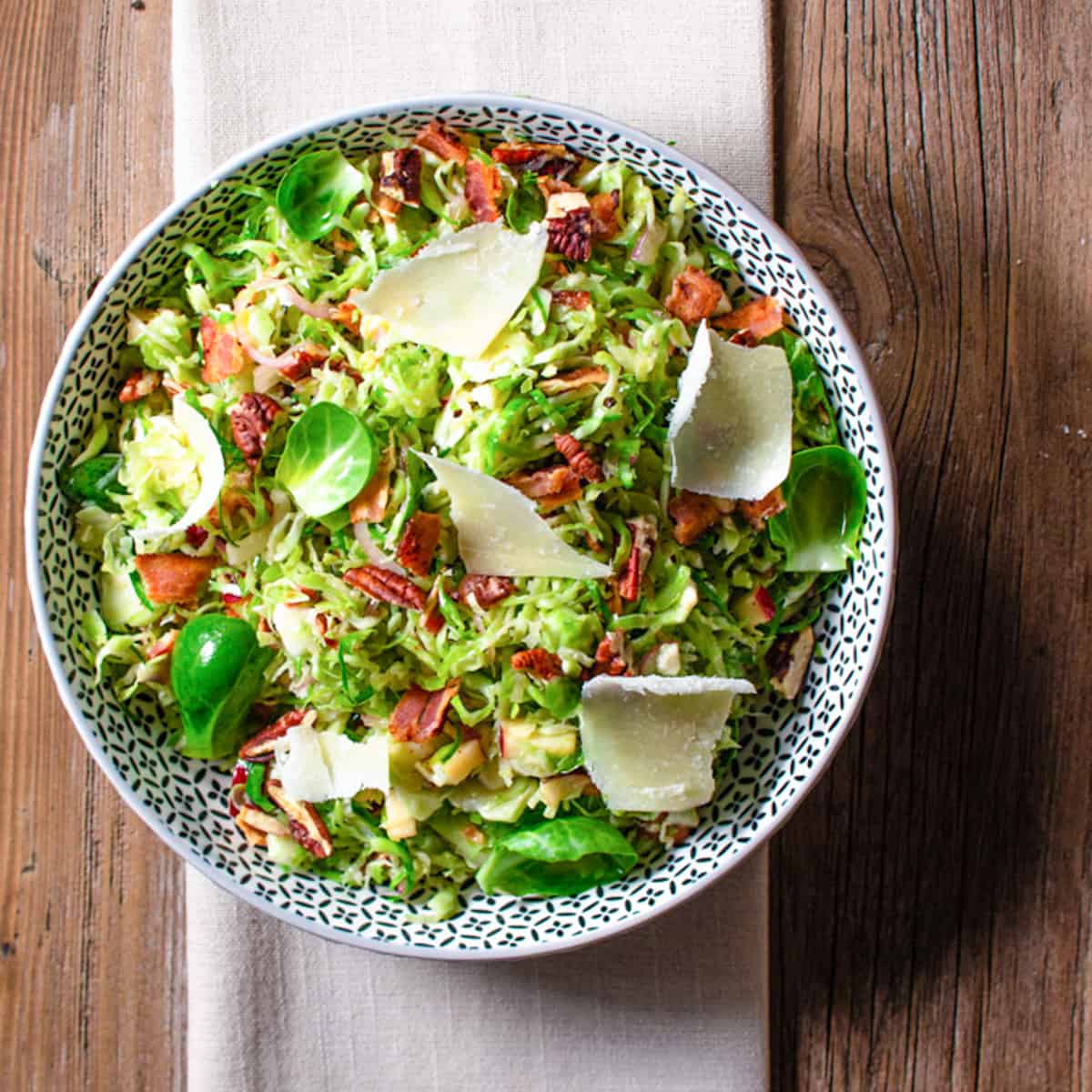 Brussels sprouts slaw in a bowl sitting on top of a linen napkin.