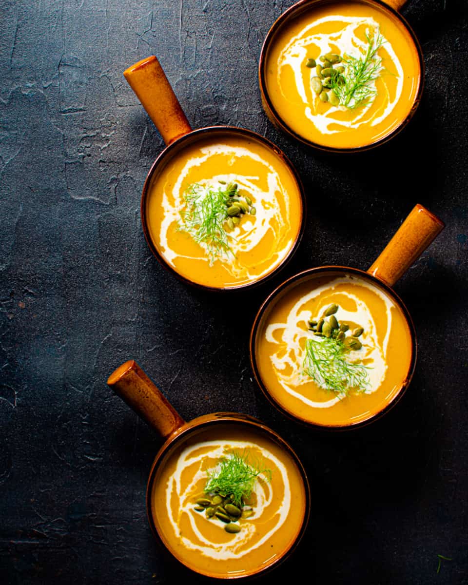 4 small bowls of soup on a black backdrop. 