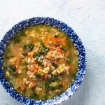 white bean sausage and arugula soup in blue bowl