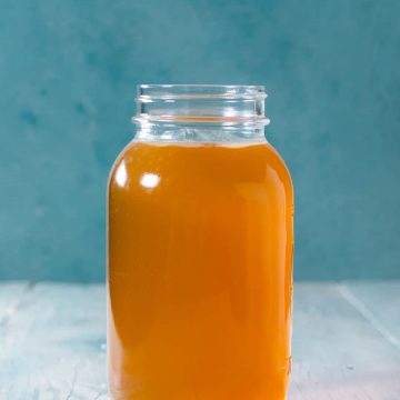 One liter mason jar of chicken stock with blue background