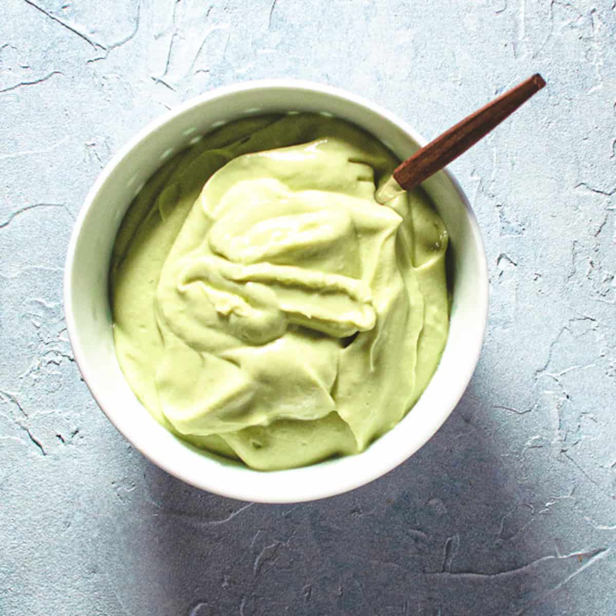 Avocado Caesar Dressing in white bowl with spoon.