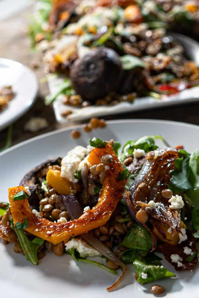 close up of single serving of warm lentil salad with roasted vegetables and bacon