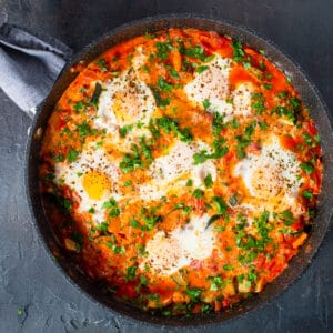 finished shakshuka in the pan garnished with fresh chopped parsley.