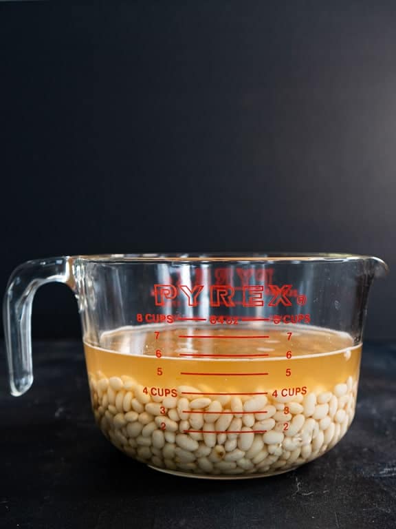 Cooked navy beans with cooking liquid, glass measuring cup