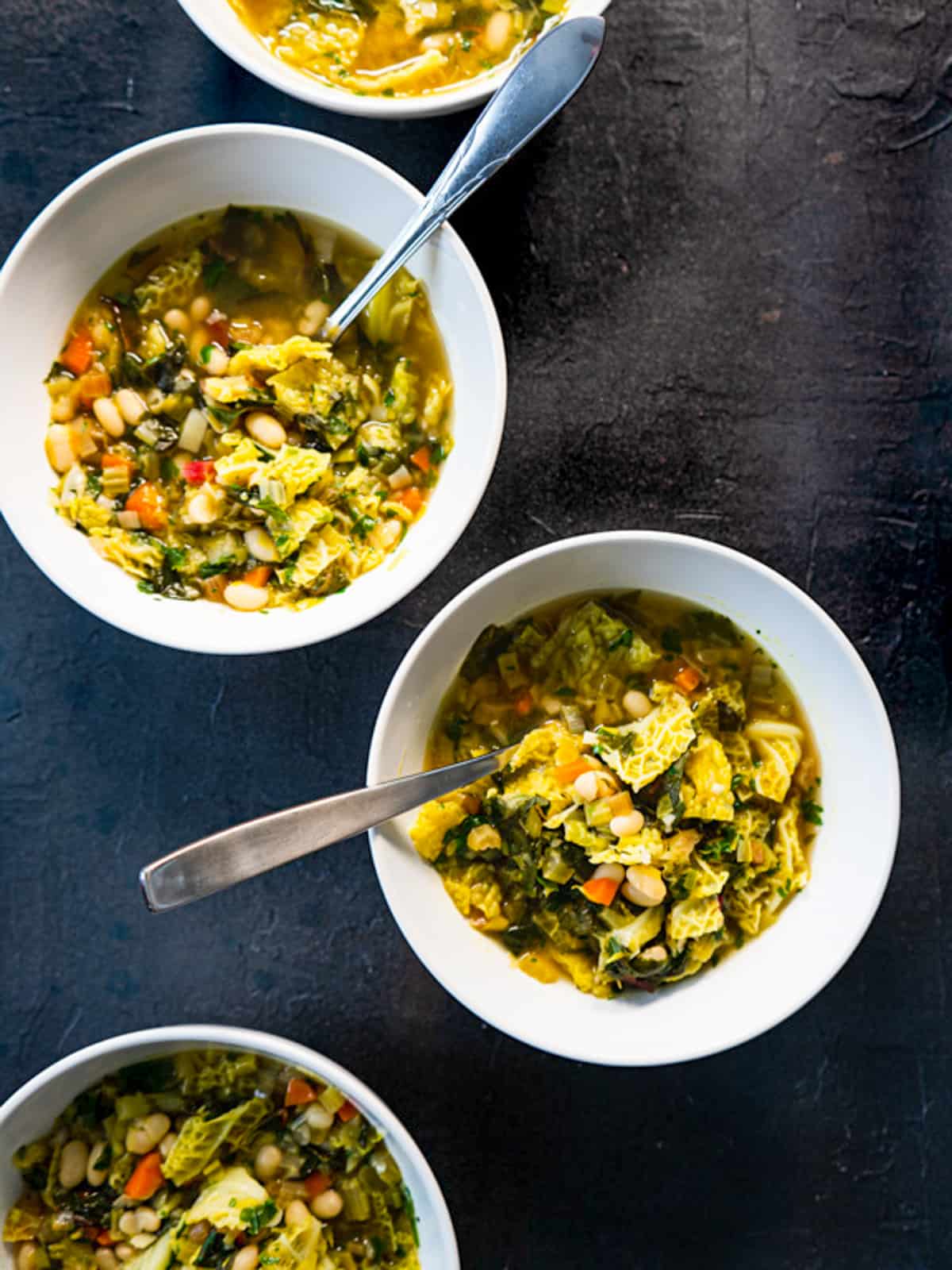 4 staggered bowls of soup on a black background.