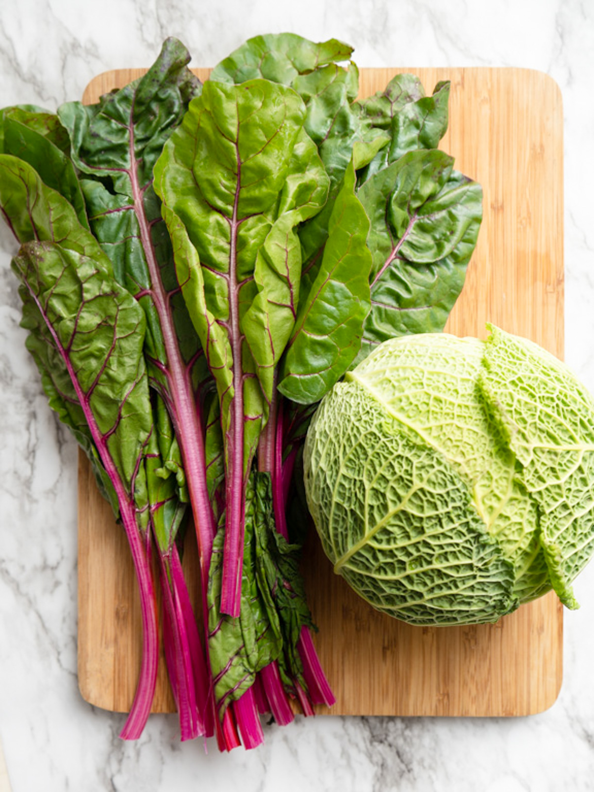 red Swiss chard and savoy cabbage on wood board.