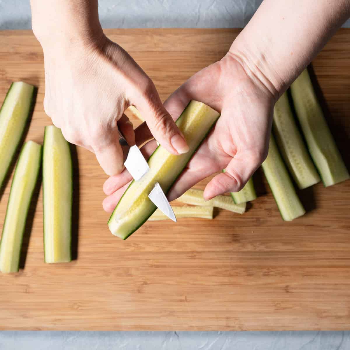 Removing seeds from cucumber with a paring knife.