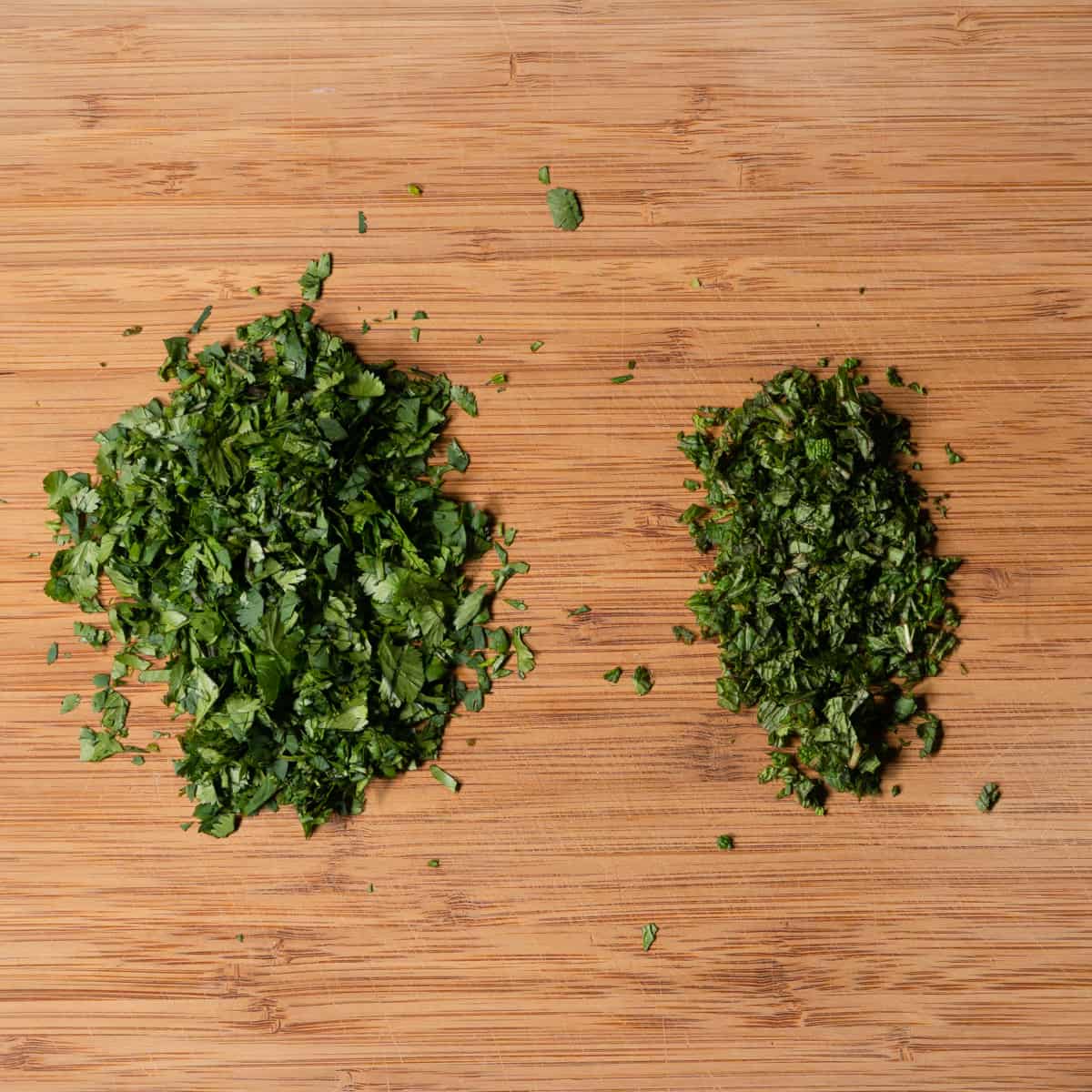 finely chopped parsley and mint on a wood cutting board. 