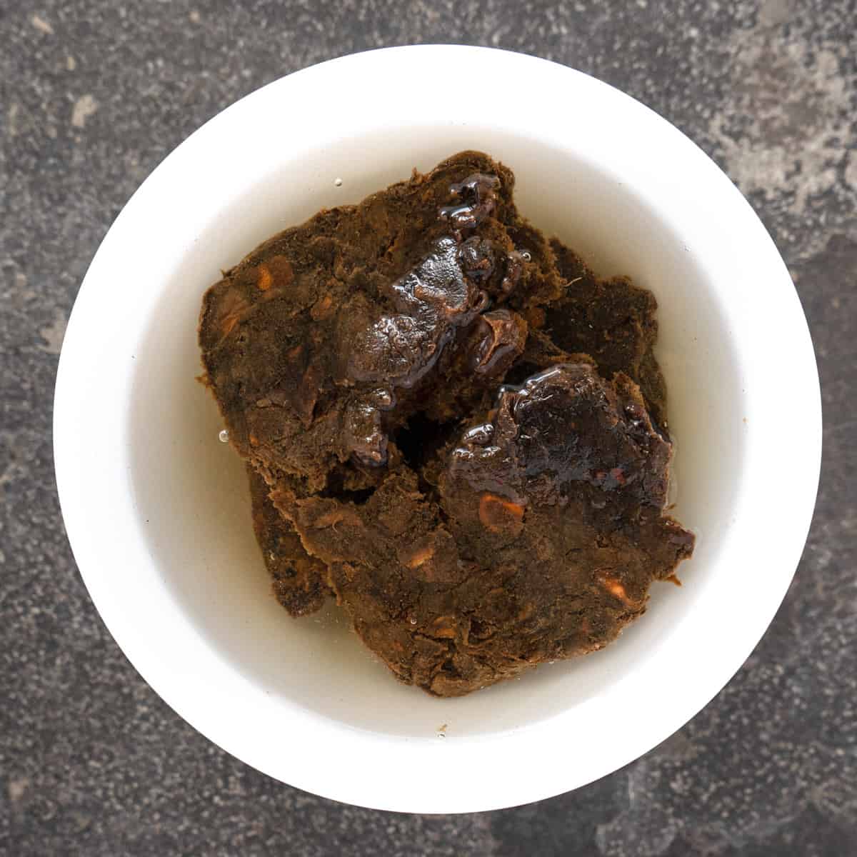 tamarind pulp with seeds soaking in hot water in a bowl. 