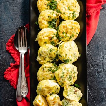 Egg bites on rectangular black platter with red napkin and fork and spoon