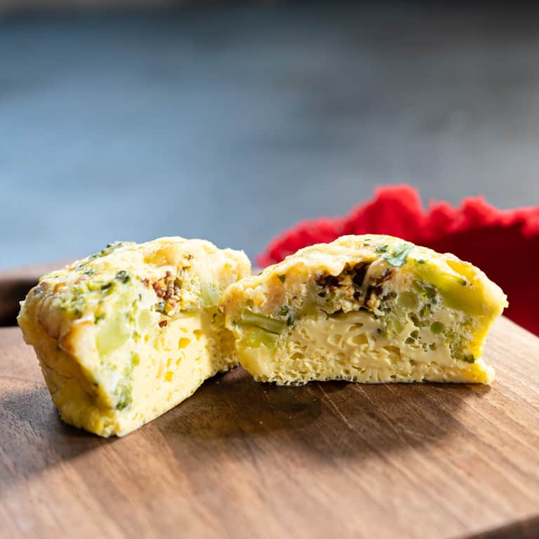 Broccoli, cheddar and Dijon egg bite cut in half on a wood board