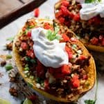 spaghetti squash stuffed with turkey taco filling topped with sour cream and tomaotes