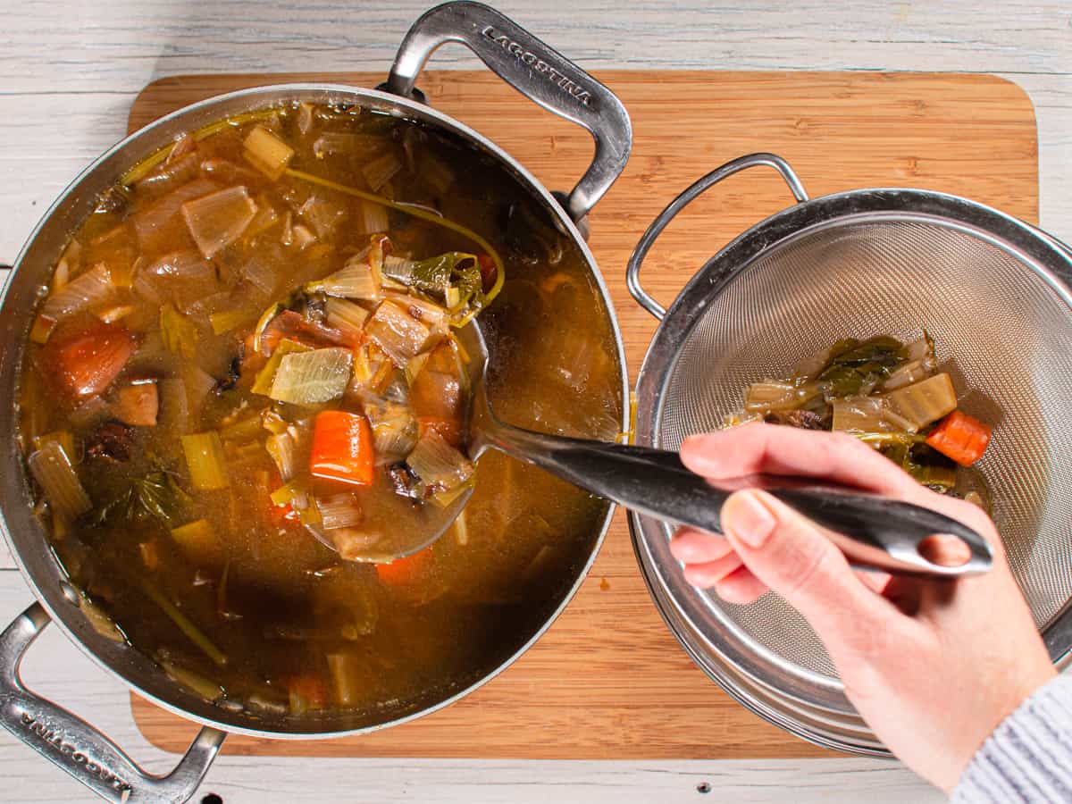 Cooked stock being strained through fine mesh strainer