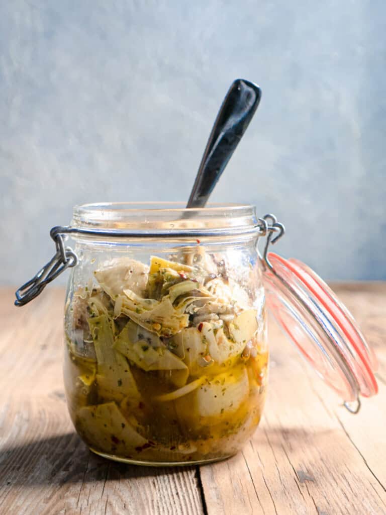 Marinated artichoke hearts in a mason jar with a spoon.