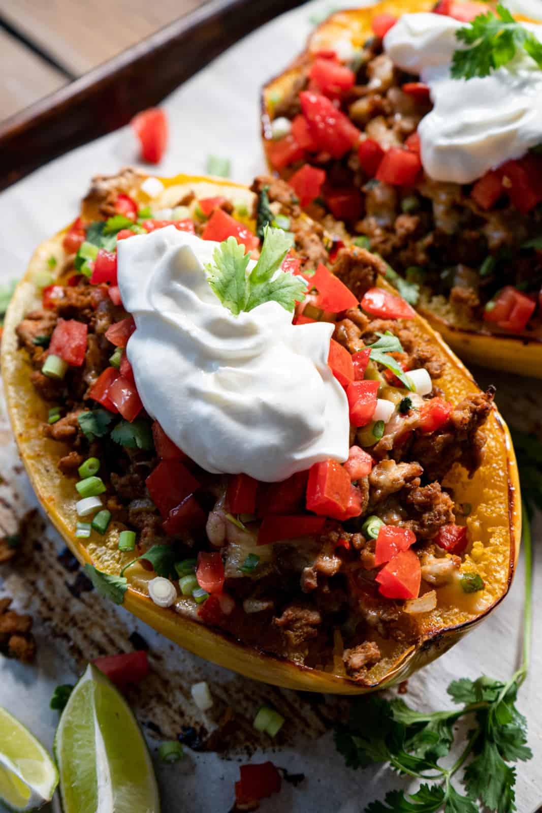 half of a stuffed and baked spaghetti squash topped with sour cream and fresh tomatoes.