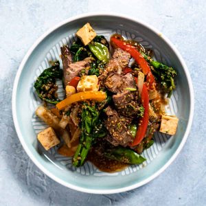 Beef stir fry on blue plate with blue background