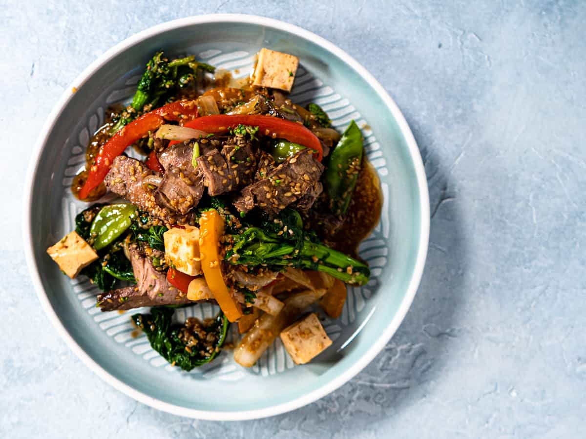 Beef stir fry on blue plate with blue background