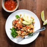 tofu scramble on white plate with avocado lime and salsa on the side.