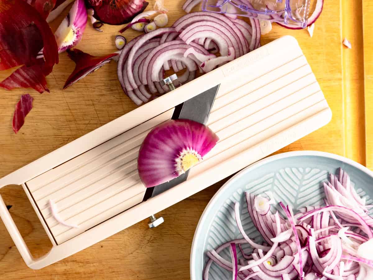 slicing red onion on a mandoline