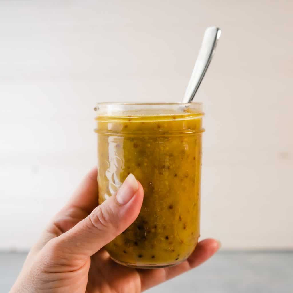 jar of honey mustard dressing held in hand with spoon