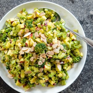 Roasted Broccoli salad on white plate with spoon on stone background