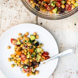 single serving of greek chickpea salad on white plate with fork