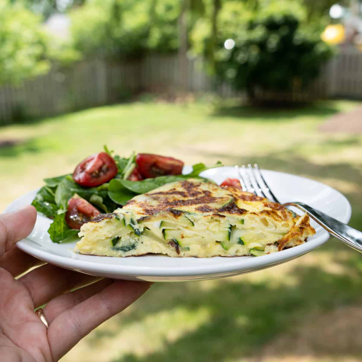 One slice of omelette with side salad on white plate