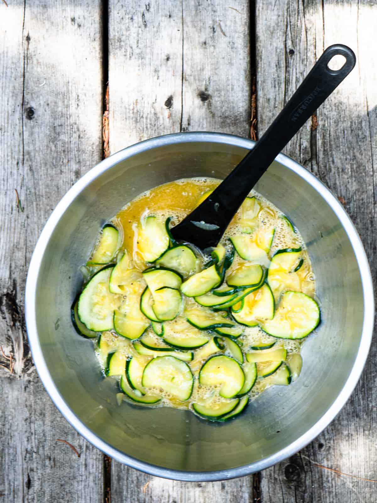 zucchini, onion, and egg mixed in a mixing bowl.