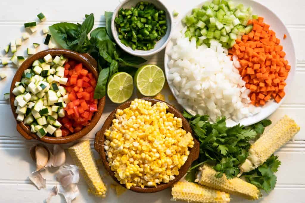 Prepared ingredients for chowder. Corn, onion, carrots, celery, red pepper, zucchini, garlic, basil, cilantro