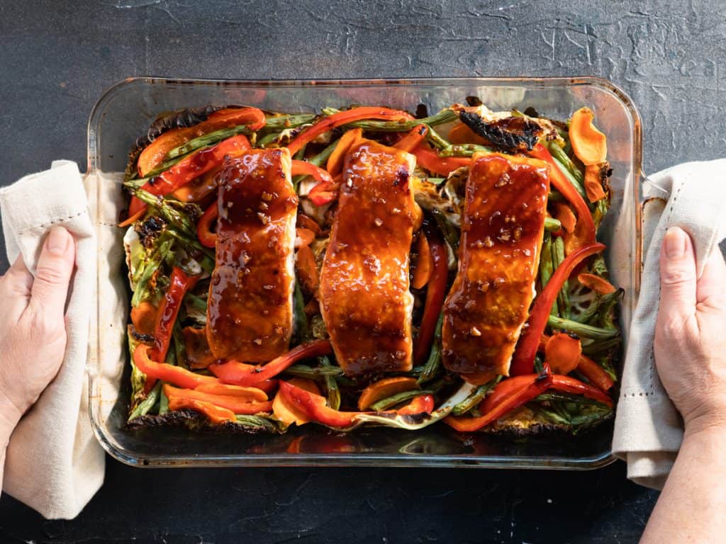 3 salmon filets with teriyaki sauce on top of vegetables. Just out of the oven in a glass dish