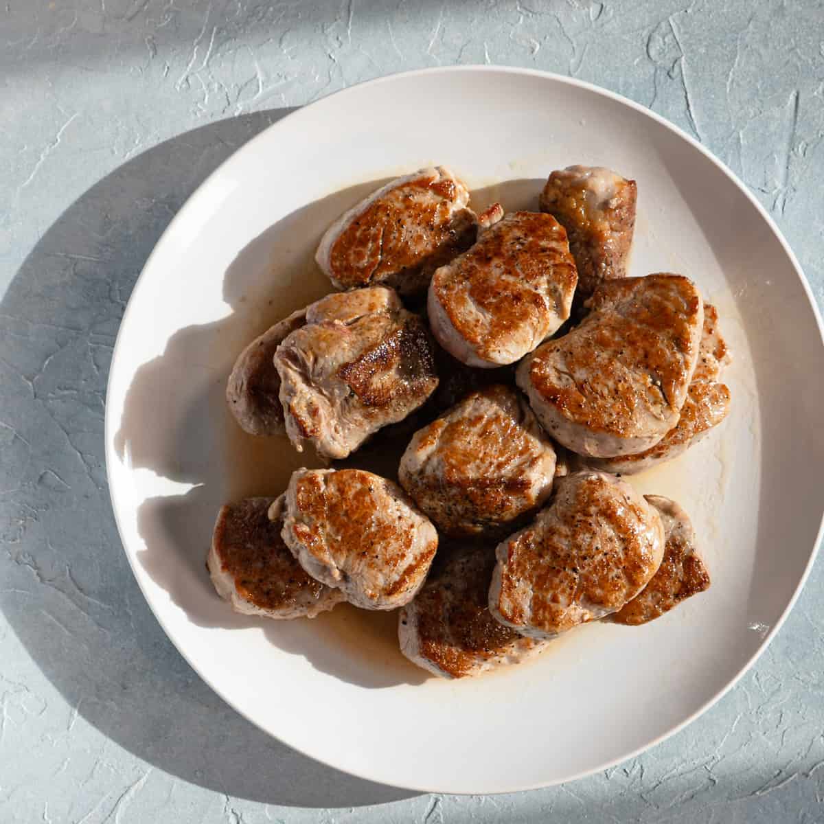 seared pork medallions on a white plate