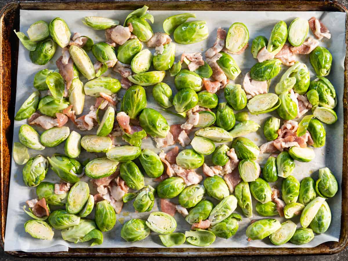 Prepared sprouts and bacon on a lined baking sheet before going into the oven.