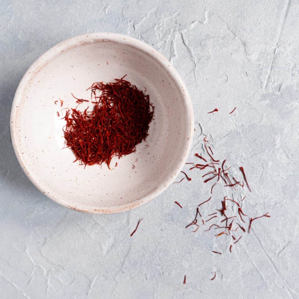 small white ceramic dish of saffron on blue background