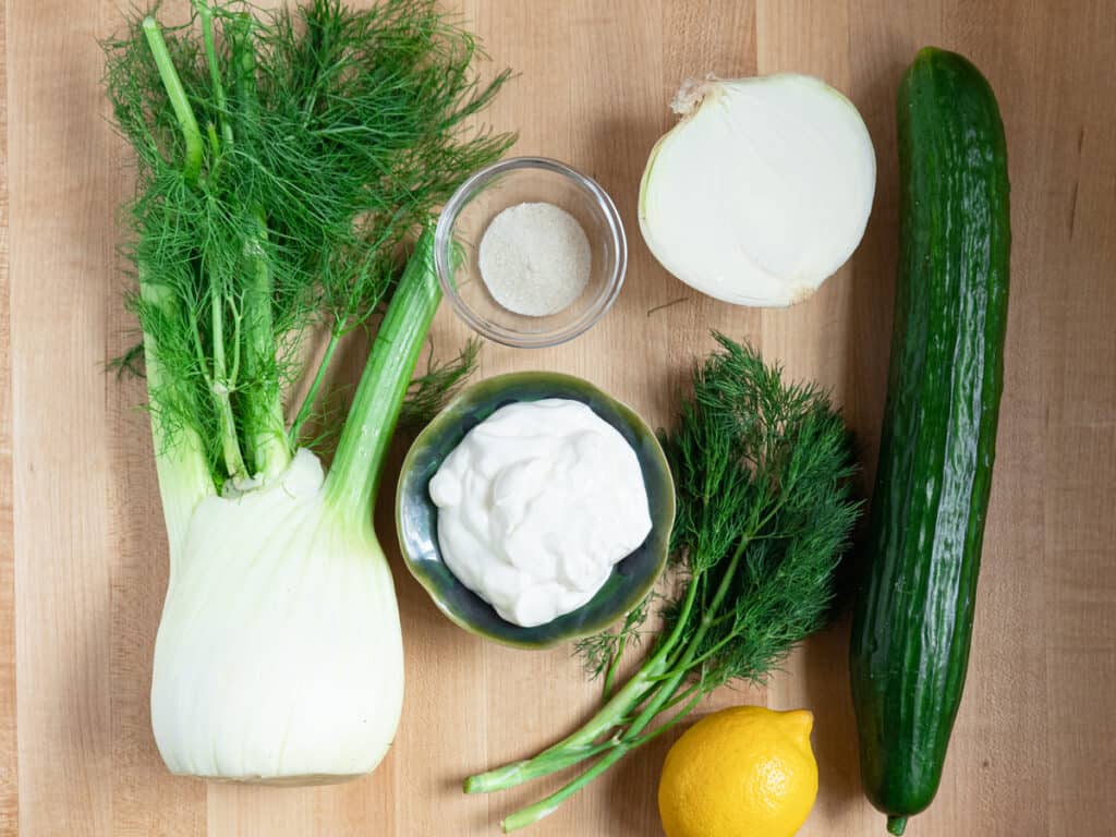 Ingredients for creamy fennel and cucumber salad on wood board