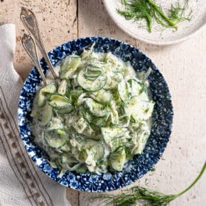 creamy fennel and cucumber salad in a blue and white bowl on a distressed white background